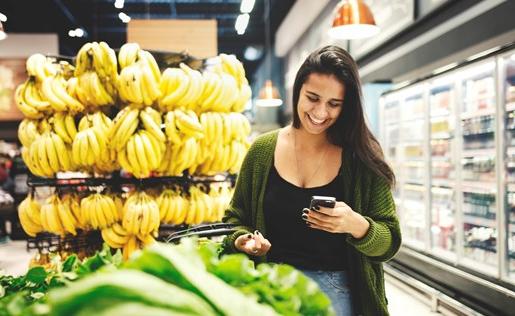 Woman in the produce department looking at her phone.